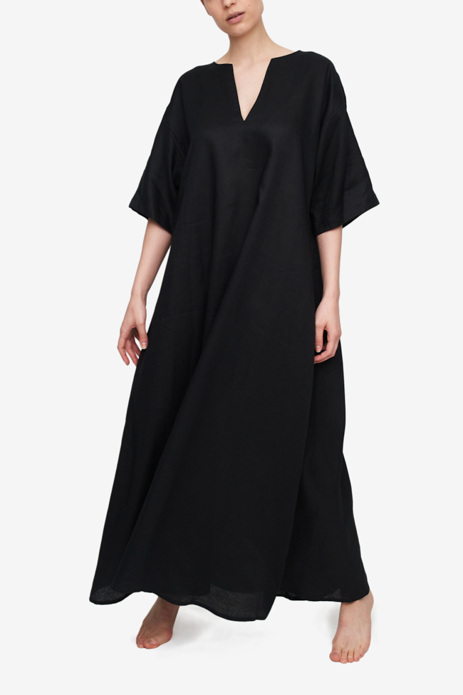 A full length black linen caftan with wide, elbow length sleeves. The neckline is a slit, showing a small V of cleavage. 