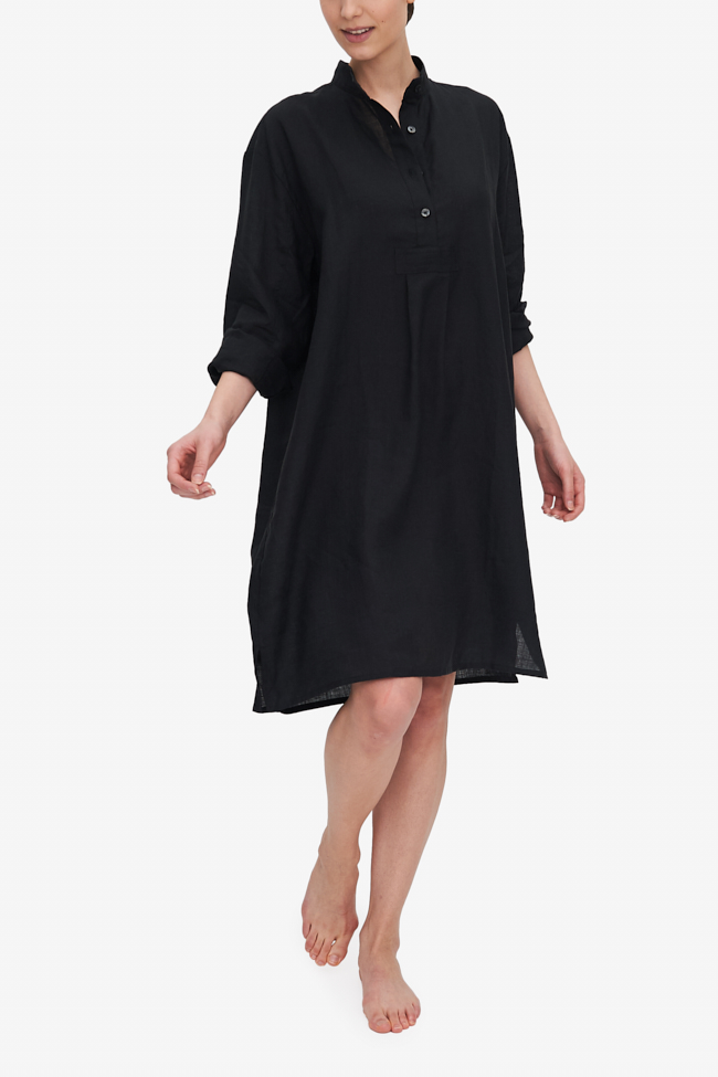 A woman takes a step and the nightshirt she is wearing moves around her. The Black linen looks both crisp and soft all at once. The Sleeves are rolled up to three-quarter length.