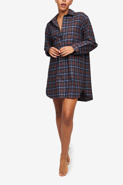 An oversized button up traditional mens style boyfriend shirt. A black based plaid with white, blue and red check. Pointed collar and long sleeves, curved hem.