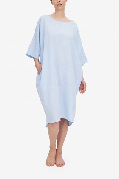 Emily wears our Pocket Kaftan in a gorgeous light blue linen and cotton blend fabric. The model has her hand in the pocket, and the cocoon silhouette can be seen .