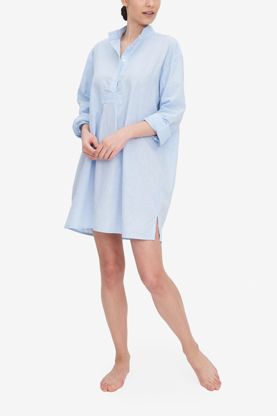 Emily wears our Short Sleep Shirt - a traditional, oversized shirt - made from a light blue linen and cotton blend fabric. 