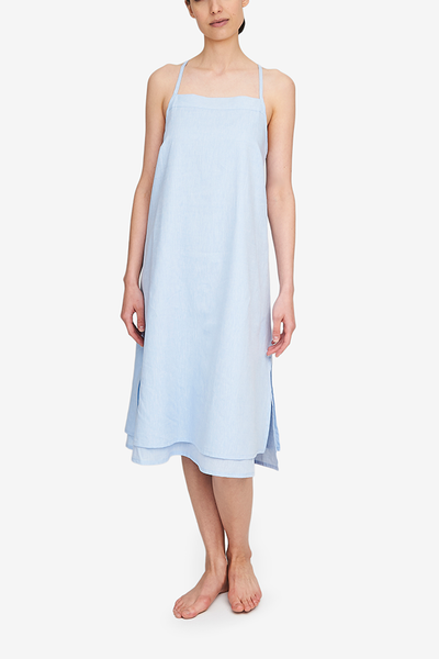 Front view of the Two Layer Dress, shown here in a light blue cotton and linen blend. The dress has a square neckline, spaghetti straps that cross in the back and a double layer body with different hem lengths - the outer layer is a couple inches shorter. Side slits make this shape sway and move when being worn.