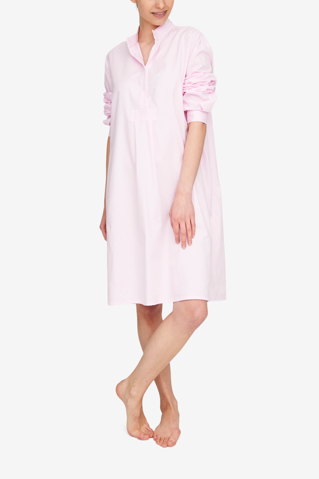 A textured Royal Oxford Cotton in a light pink colour shown in our Long Sleep Shirt shape. The wearer stands with her ankles crosse and arms hanging loosely at her sides. The full length sleeve are pushed up to her elbows.  