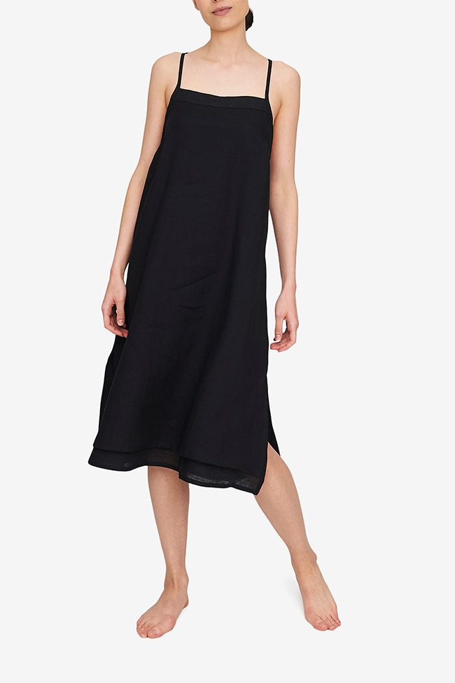 Front view of the Two Layer Dress, shown here in black linen. The dress has a square neckline, spaghetti straps that cross in the back and a double layer body with different hem length - the outer layer is a coupe inches shorter. Side slits make this shape sway and move when being worn. 