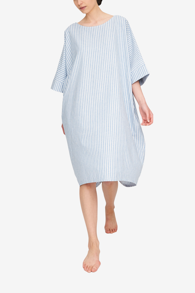 The Pocket Kaftan in a blue and white striped cotton linen blend. The model is taking a step towards the camera, showing off the cocoon silhouette. 