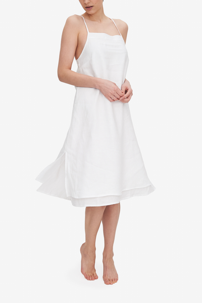 Front view of the Two Layer Dress, shown here in white linen. The dress has a square neckline, spaghetti straps that cross in the back and a double layer body with different hem lengths - the outer layer is a couple inches shorter. Side slits make this shape sway and move when being worn.