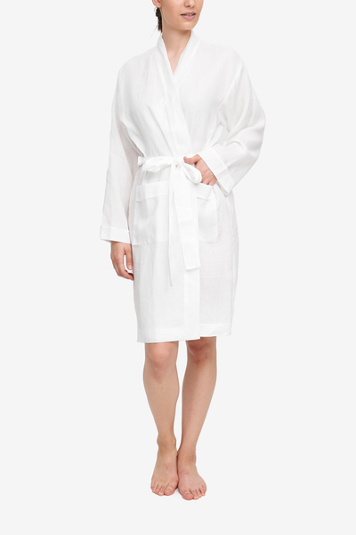 White linen robe with patch pockets and matching belt. Long sleeve and shawl collar. Knee length.
